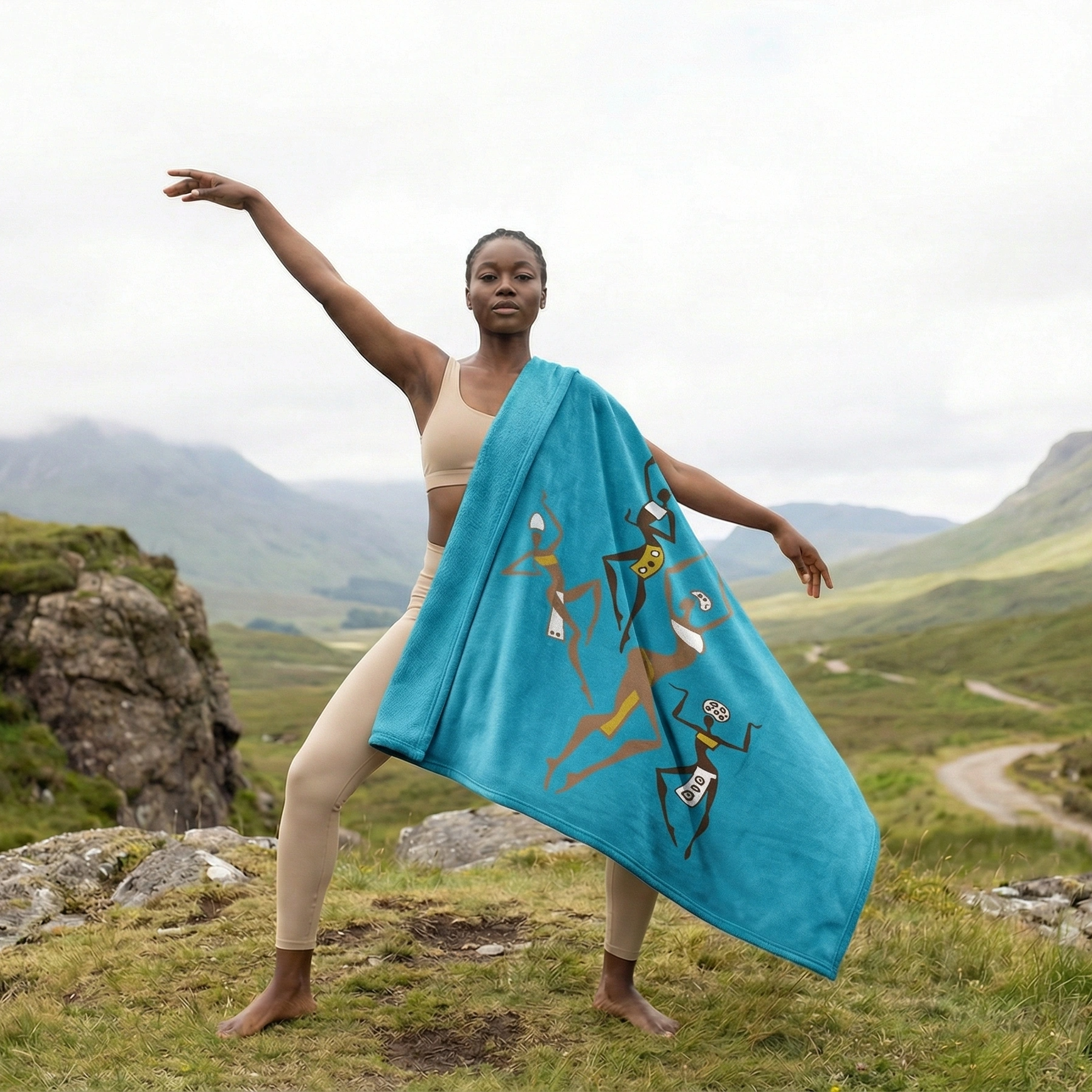 Lifestyle image of a person standing outdoors wrapped in a turquoise African tribal dancers fleece blanket, showcasing cultural artwork, warmth, and versatility in nature