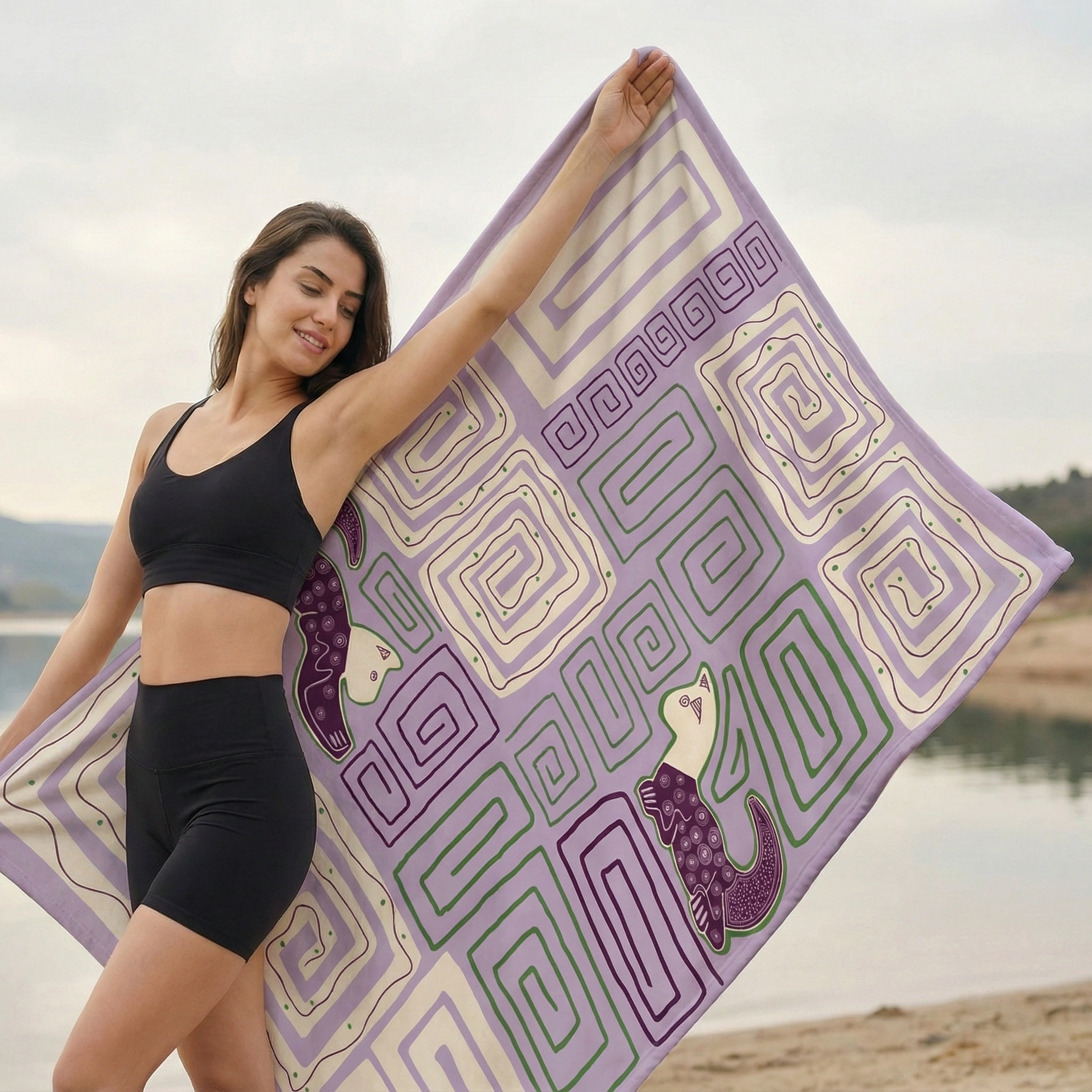 Person stretching outdoors while holding a purple yoga blanket decorated with geometric maze-style patterns.