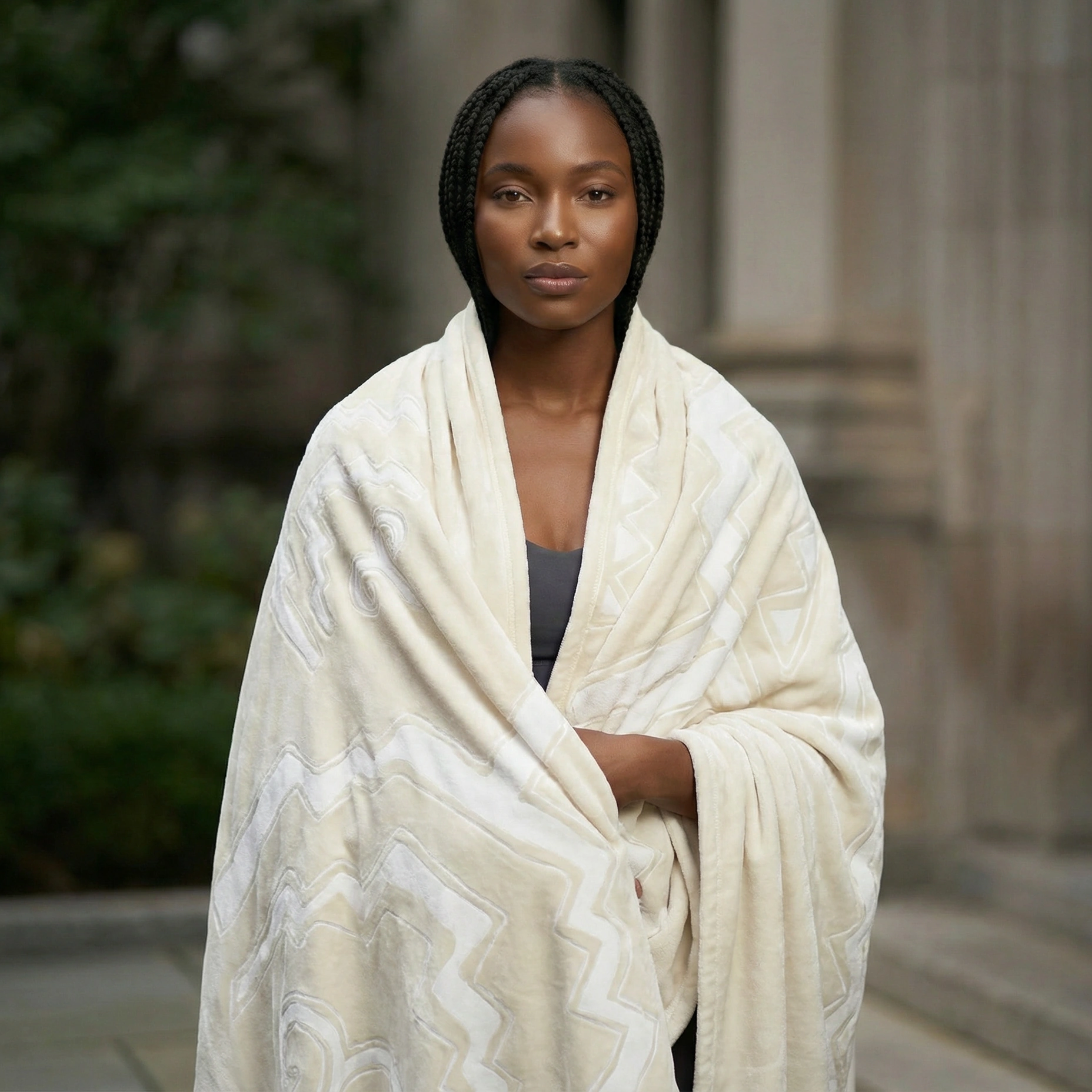 Person standing outdoors wearing a white meditation blanket featuring embossed geometric patterns.