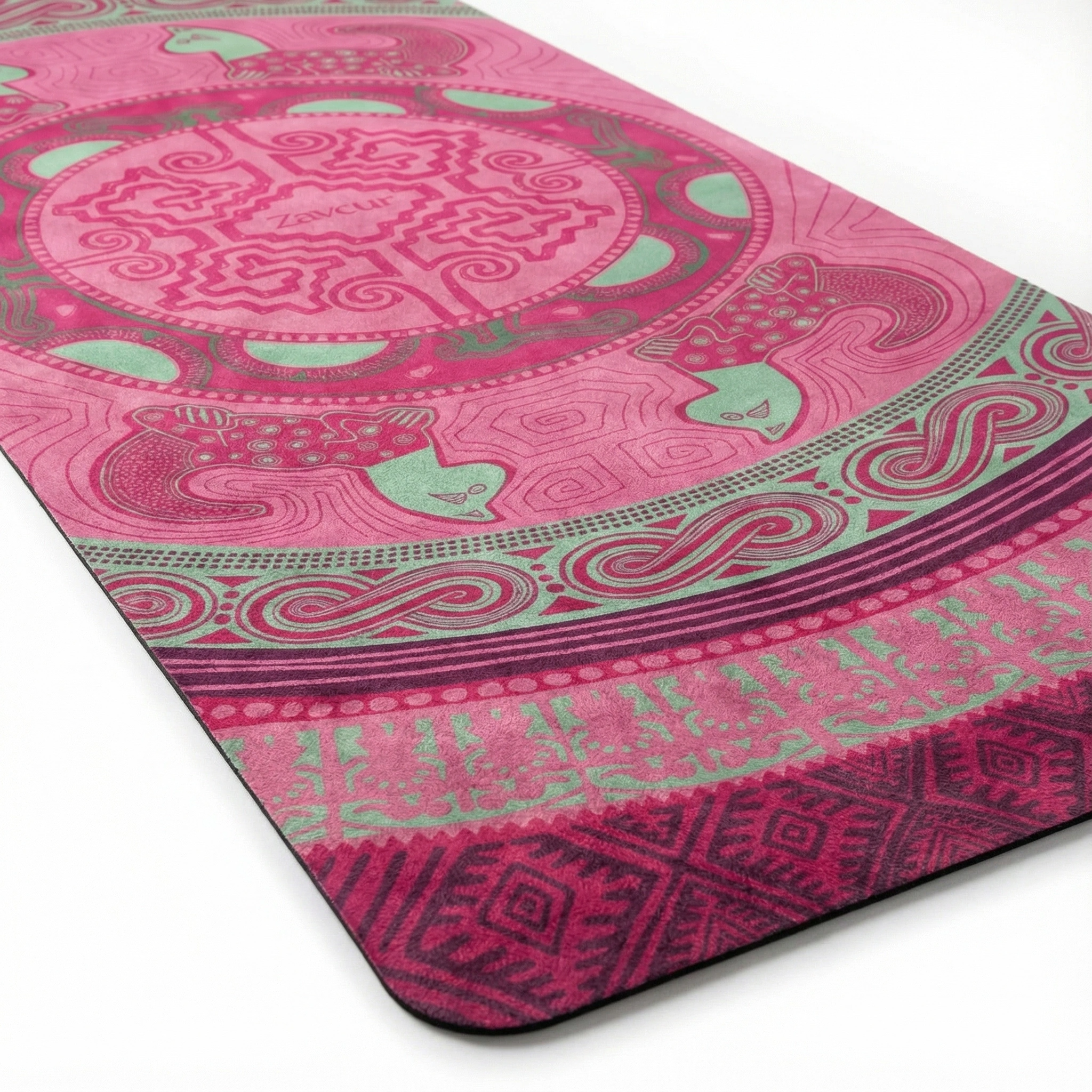 Corner detail of pink yoga mat with mint green peacock accents showing mandala medallion, yin yang symbol, spiral wave borders, tribal geometric patterns, and textured non-slip surface