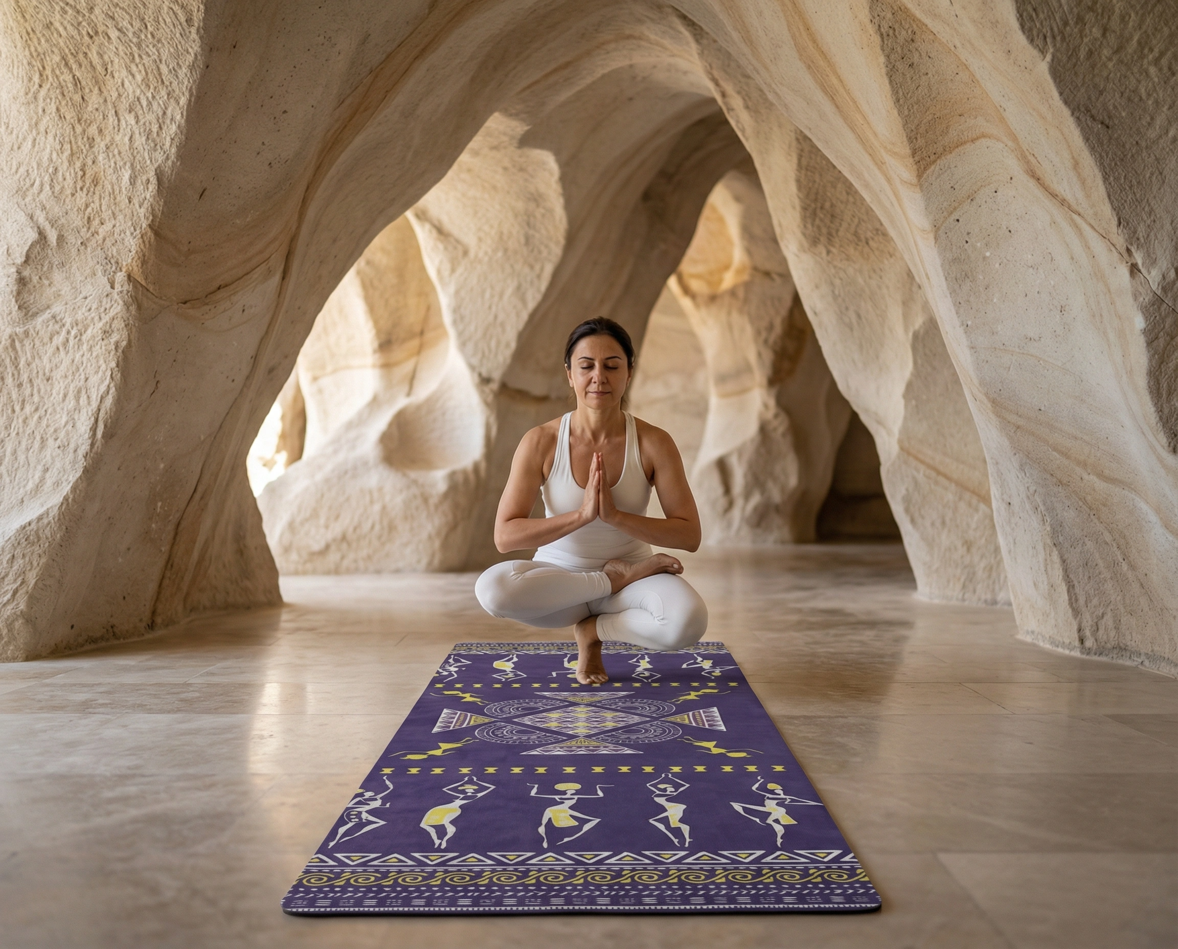Woman meditating in lotus position with prayer hands on purple yoga mat inside organic shaped cave